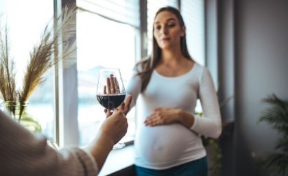 Image, Adobe. Pregnant woman declining glass of red wine. Adobe